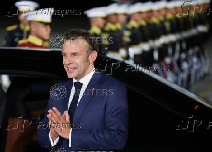 French President Emmanuel Macron gestures upon his arrival at military airbase Halim Perdanakusuma in Jakarta