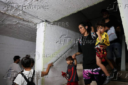 People take shelter during a siren as missiles are launched from Iran towards Israel