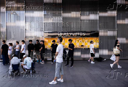 People gather outside a Louis Vuitton store at the Central Business District in Beijing