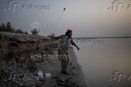 Man fishes from the bank of the Chenab River in Multan, Pakistan