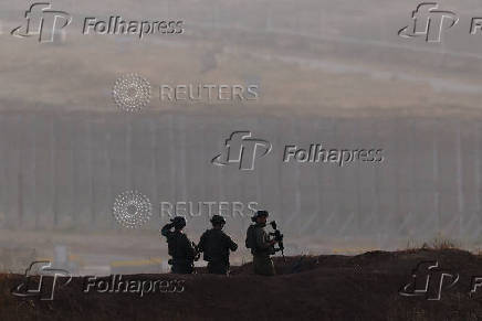 Soldiers stand on the Israeli side of the Israel-Gaza border