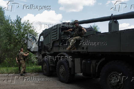 Ukrainian servicemen are seen next to a self-propelled howitzer before firing towards Russian troops near a front line in Kharkiv region
