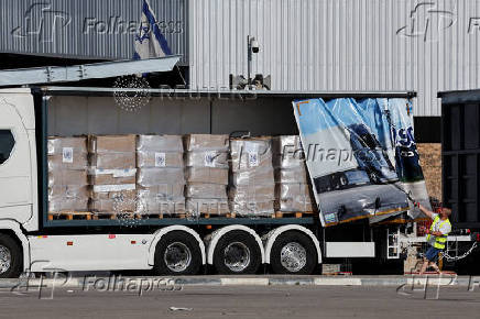 A worker displays the supplies in a truck carrying aid at the Kerem Shalom crossing between Israel and Gaza, on the Israeli side of the Israel-Gaza border