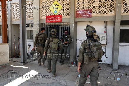 Israeli soldiers walk by the entrance to the European Hospital in Khan Younis at the Gaza Strip, where they found a tunnel underneath it