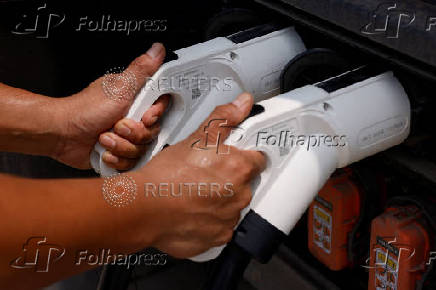 Truck driver puts charging plugs into a Sany electric heavy truck at a charging station in Langfang, Hebei