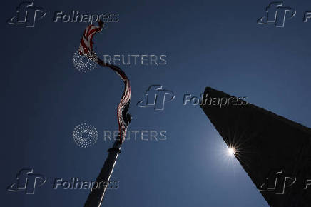 The sun peeks out from behind the Washington Monument during a heatwave affecting the eastern U.S., in Washington