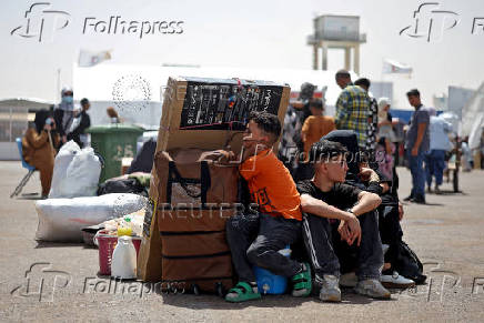 An Afghan family deported from Iran rests with their belongings at a camp for returning migrants near Islam Qala border crossing