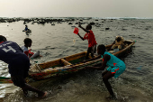 Children play as fishermen on a boat at the fishing port in Yoff beach