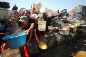 Palestinians wait to receive food from a charity kitchen, in Gaza City