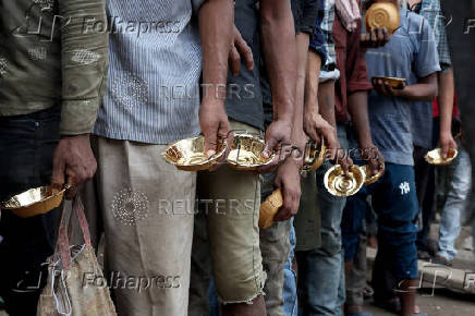 Labourers wait in line to receive free food being distributed at a wholesale market