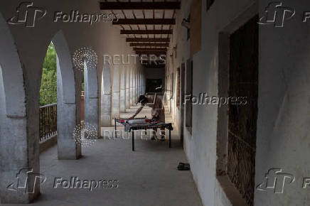 Teen makes bed outside dormitory at madrasa in Multan