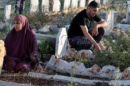 Palestinians visit graves of their relatives at a cemetery in Jenin camp
