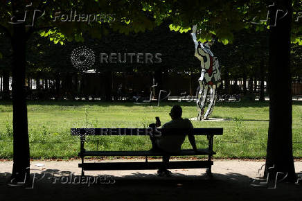 A man sits on a bench in the Tuileries Garden on a warm and sunny day in Paris