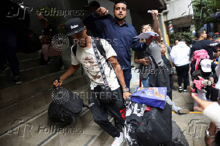 Migrants gather outside the Venezuelan embasssy waiting for a flight back to their country