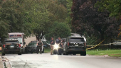 Police stand at a crime scene as they searched for a suspect posing as a police officer who shot two Democratic state lawmakers