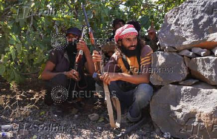Armed men sit together with their weapons after Syrian troops entered the predominantly Druze city of Sweida