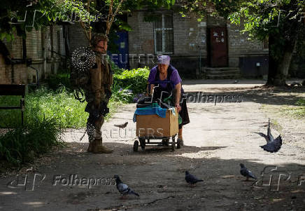 A resident pulls a cart near a Ukrainian serviceman in the frontline town of Kostyantynivka