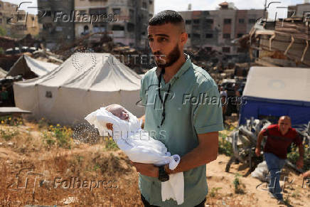 A Palestinian mourner carries the body of the stillborn baby of Palestinian woman Seham Al-Arabeed, who was killed in an a Israeli strike, according to medics, at a cemetery in Gaza City