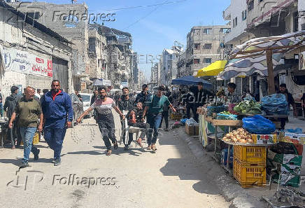 Palestinians carry a victim after an Israeli airstrike, in Gaza City
