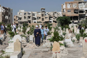People visit the graves of their relatives at a cemetery, on the first day of the Muslim holiday of Eid al-Adha, in Damascus