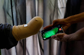Technician uses a mobile phone for 3D scan of a patient before develping a prosthetic limb at Bioniks Private Limited, in Karachi