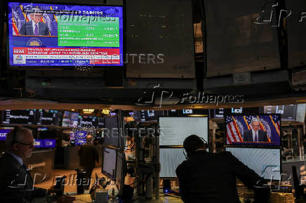 Traders work, as screens broadcast a press conference by U.S. Federal Reserve Chair Jerome Powell following the Fed rate announcement, on the floor of the NYSE in New York