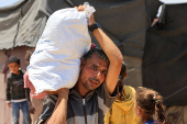 Palestinians carry aid supplies they received from the U.S.-backed Gaza Humanitarian Foundation, in Khan Younis