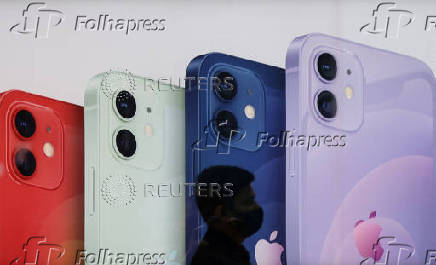 FILE PHOTO: A salesperson walks past an advertisement at an Apple reseller store in Mumbai
