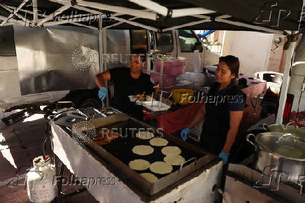 Workers from Guatemala prepare tortillas on a street booth selling, in Los Angeles