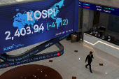 People pass by a screen showing KOSPI at the Korea Exchange in Seoul