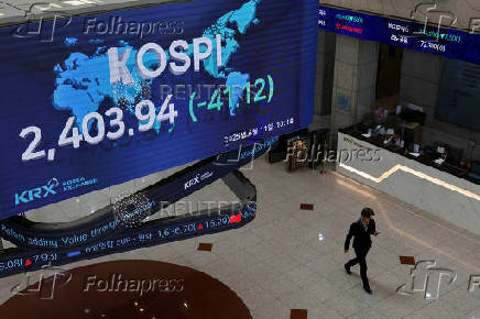 People pass by a screen showing KOSPI at the Korea Exchange in Seoul