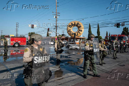 Los Angeles County Sheriff's deputies maintain a cordon along Atlantic Boulevard during a standoff with protesters in Paramount