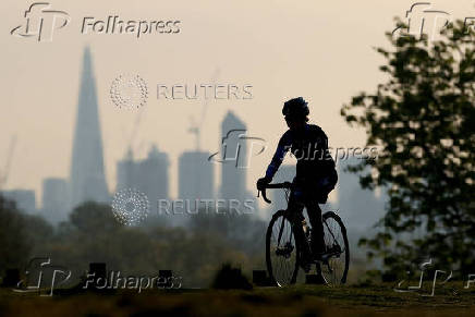 FILE PHOTO: A person cycles in Richmond Park, with the city skyline in the background, in London