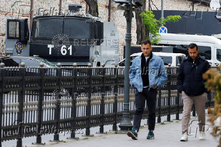 Men walk near a security vehicle outside the Turkish Presidency's Dolmabahce working office, in Istanbul