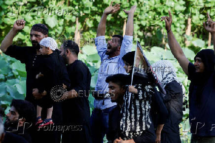 Shi'ite mourners shout religious slogans as they ride on boats in the interiors of Dal Lake during a Muharram procession ahead of Ashura in Srinagar