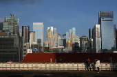 A photographer takes photos of a cosplayer in the backdrop of the central business district skyline in Singapore