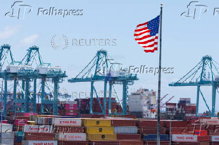 FILE PHOTO: The American flag flutters near a ship at the Port of Los Angeles