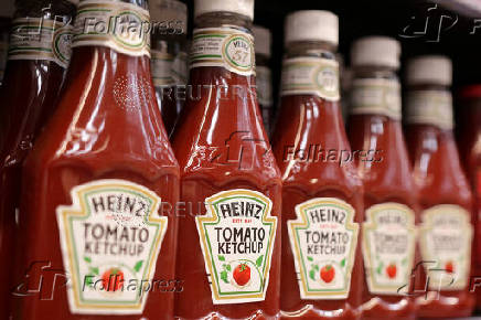 Bottles of Heinz Ketchup are displayed on a shelf in a supermarket