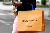 FILE PHOTO: A woman walks with a Louis Vuitton shopping bag in Paris