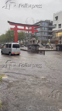 Cars drive on a flooded road amid inclement weather due to Typhoon Peipah, in Kamakura