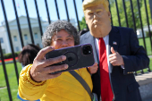 A tourist uses an Apple iPhone to take a selfie with a Trump impersonator near the White House in Washington