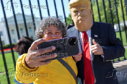 A tourist uses an Apple iPhone to take a selfie with a Trump impersonator near the White House in Washington