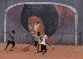 Men play soccer near a graffiti mural in Yoff, neighborhood of Dakar