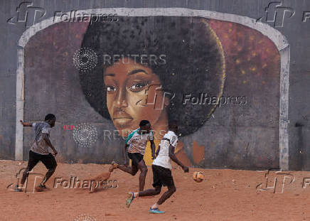 Men play soccer near a graffiti mural in Yoff, neighborhood of Dakar