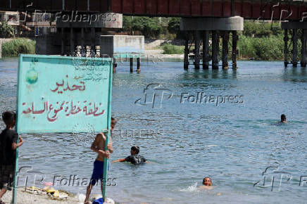 People swim in the Euphrates River during a hot day in Raqqa