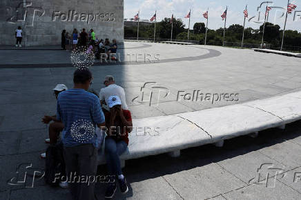 Tourists seek relief in the shade created by the Washington Monument during a heatwave affecting the eastern U.S., in Washington