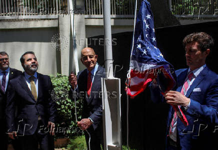 Syrian Foreign Minister Asaad Hassan al-Shibani stands next to U.S. envoy for Syria Thomas Barrack as he raises the American flag at US ambassador's residency in Damascus