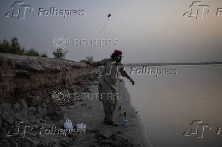 Man fishes from the bank of the Chenab River in Multan, Pakistan