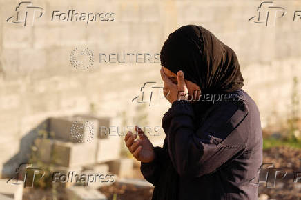 Palestinians visit graves of their relatives at a cemetery in Jenin camp
