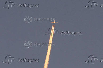 A military aircraft flies in the sky following a barrage of missiles launched from Iran, as seen over Tubas